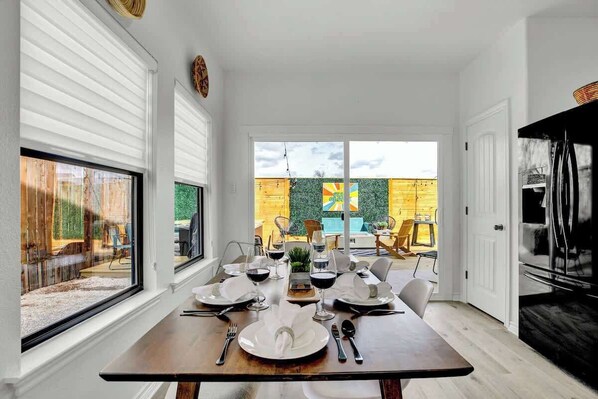 A dining area with a table set for four, large windows, and a view of the outdoors.