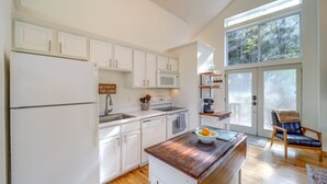 Une cuisine avec des armoires blanches, un plan de travail en bois, un four à micro-ondes et une pancarte sur laquelle on peut lire : « THE CABIN ».