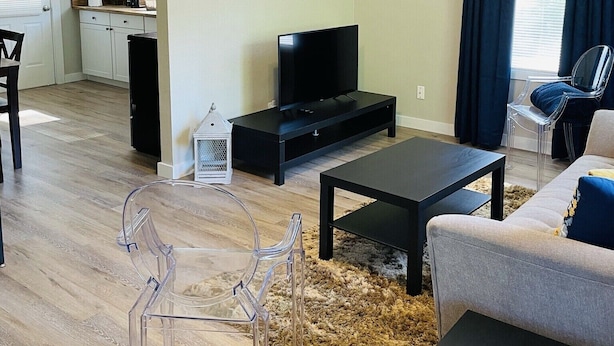 A modern living room with a flat-screen TV, a ceiling fan, and a dining area with a kitchen in the background. - Hidden Gem-10 minutes to DT Chatt! Perfect for teleworkers, small families, etc. (Rossville)