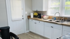 A compact kitchen with white cabinets, a wooden countertop, a sink, and a black trash bin. - Hidden Gem-10 minutes to DT Chatt! Perfect for teleworkers, small families, etc. (Rossville)