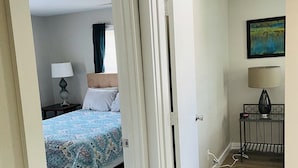 A hotel room with a bed, a bedside table with a lamp, and a painting on the wall. - Hidden Gem-10 minutes to DT Chatt! Perfect for teleworkers, small families, etc. (Rossville)