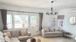 A living room with a sofa, a round coffee table, a lamp, a chandelier, and a view through large windows. - Villa with private pool, pool table & Sea Views – Short Walk to Beach & Town (Mijas)
