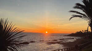 A sunset over the ocean with a wooden walkway and palm trees. - Villa with private pool, pool table & Sea Views – Short Walk to Beach & Town (Mijas)