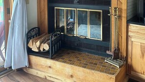 A living room with a fireplace, a television mounted above it, and a wooden cabinet to the right. - Newly decorated 2 BR 2 bath Sleeps 6 outdoor pool, close to Torch Lake, wifi (Mancelona)
