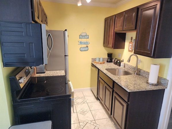 A compact kitchen with a refrigerator, stove, sink, and dark wooden cabinets. - Cozy home away from home just minutes from the Beach (Virginia Beach)