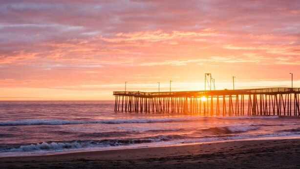 A pier extending into the ocean at sunset.
