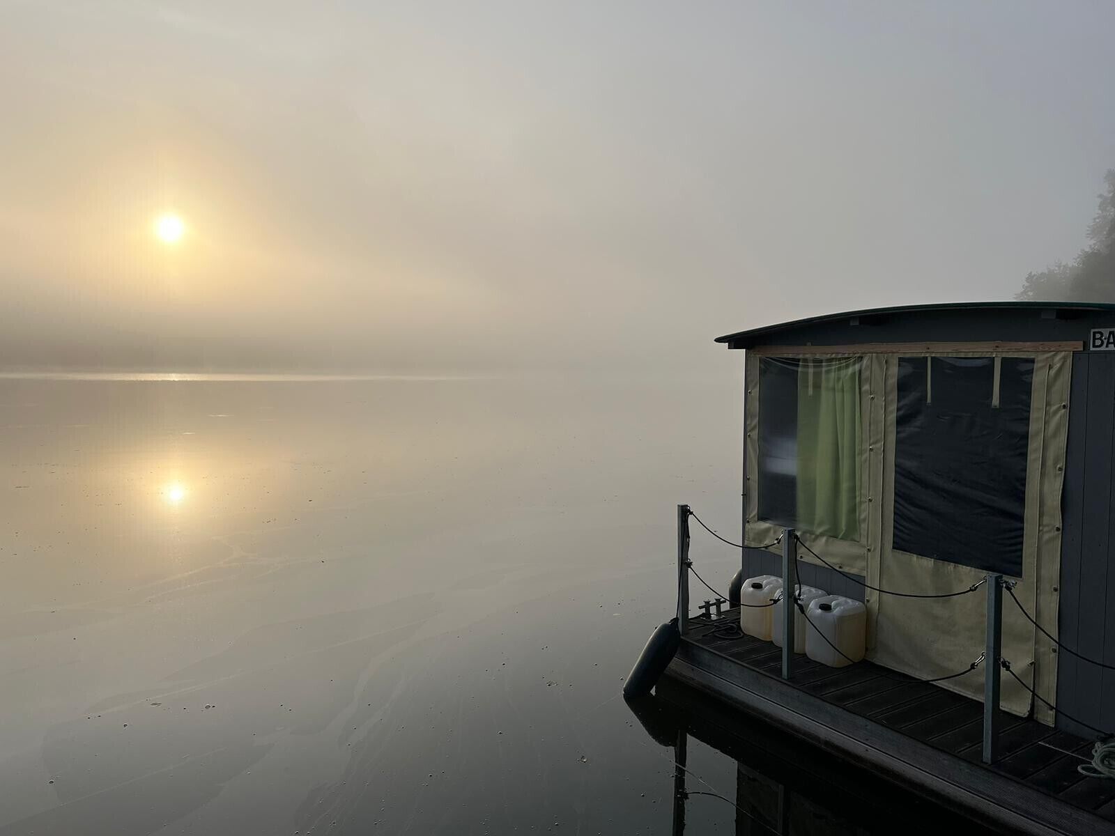A stationary boat with a cabin, a small deck area, and a view of the calm water.