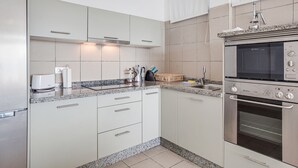 Eine moderne Küche mit weißen Schränken, einem eingebauten Ofen und einer Arbeitsplatte aus Granit.