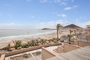 A coastal view with a beach, palm trees, and a mountain in the background. - Vacation Apartment "Casa Médano 18" with Sea & Mountain Views & Wi-Fi (Granadilla de Abona)