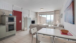 Eine moderne Küche mit integriertem Backofen und Mikrowelle, ein Essbereich mit Tisch und Stühlen sowie eine Wohnbereich mit Sofa und Fernseher.