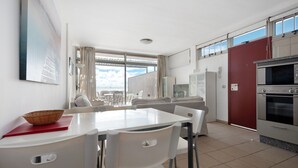 Une cuisine moderne avec un coin repas, de grandes fenêtres et un four rouge.