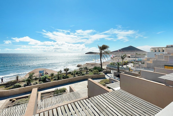 A coastal view with a beach, ocean, and a mountain in the distance.