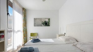 Une chambre d’hôtel avec deux lits, une fenêtre avec des rideaux, une œuvre d’art accrochée au mur et un appareil Philips sur le côté gauche.