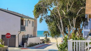 Eine Wohnstraße mit Stoppschild, einem Gebäude inklusive Garage und Blick auf den Strand.