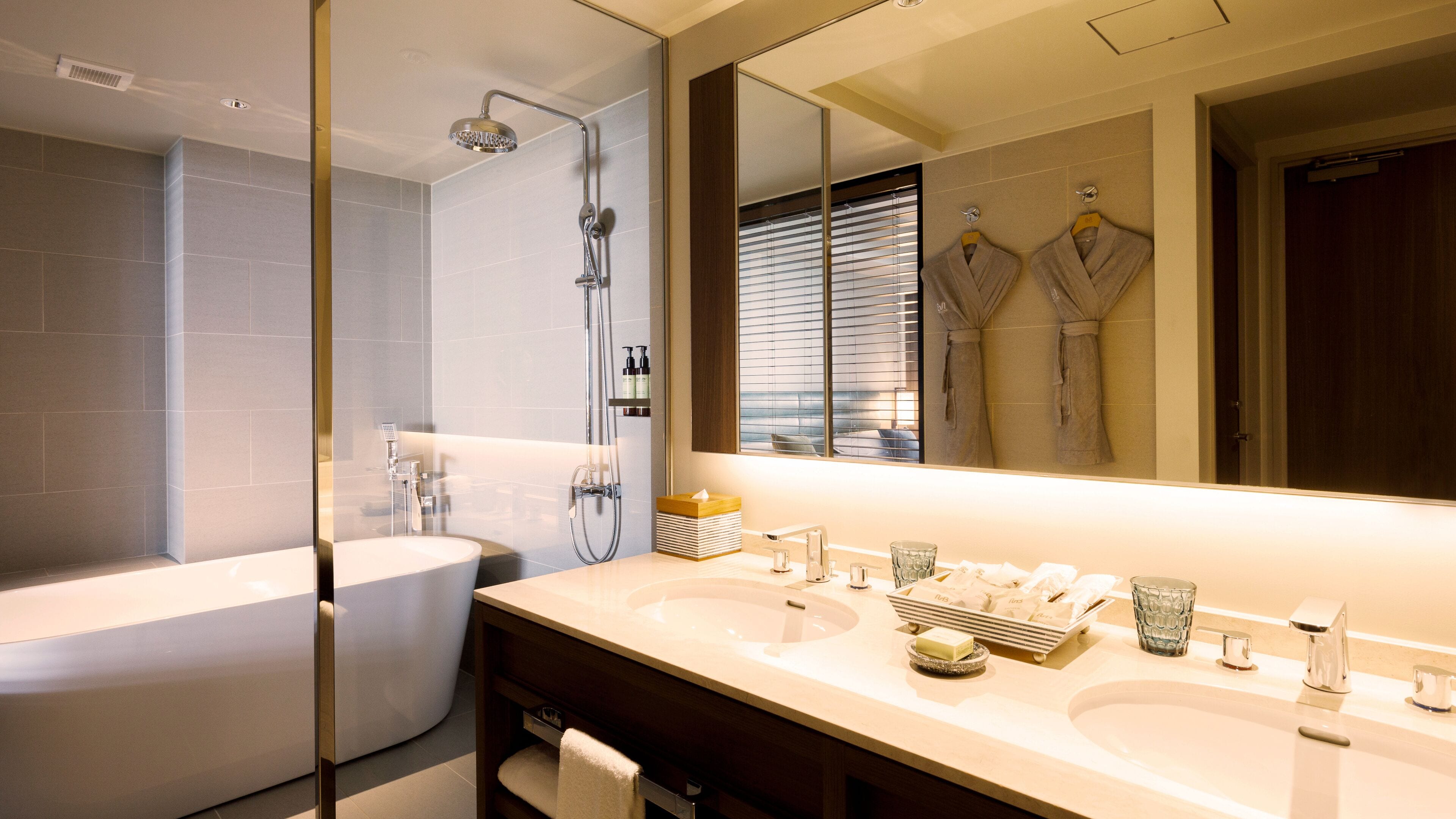 A modern bathroom with a bathtub, a shower, and a vanity with two sinks.