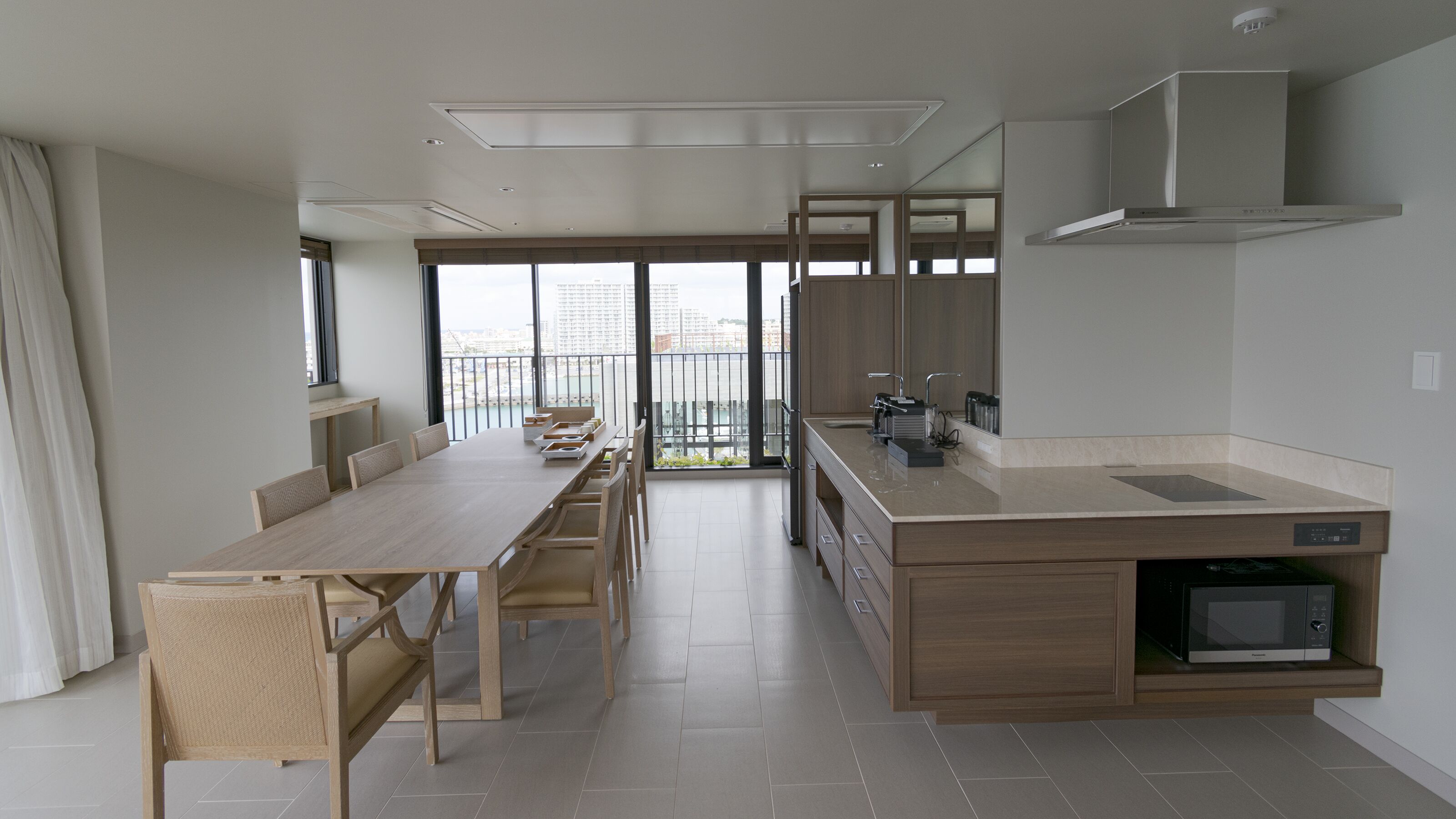 A modern kitchen with a dining area, large windows, and a view of the city.