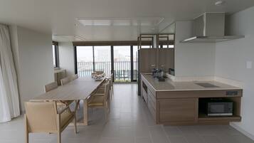 A modern kitchen with a dining area, large windows, and a view of the city.