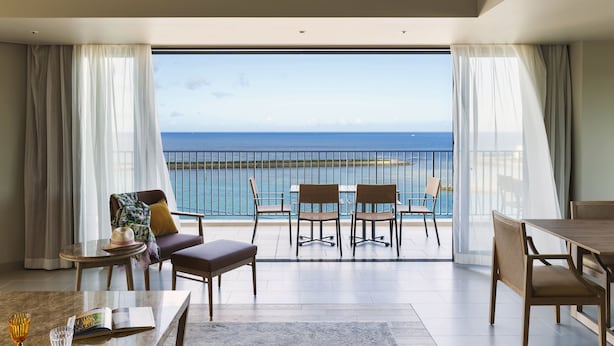 Ein geräumiger Balkon mit Meerblick, ausgestattet mit Tisch, Stühlen und einer Couch.