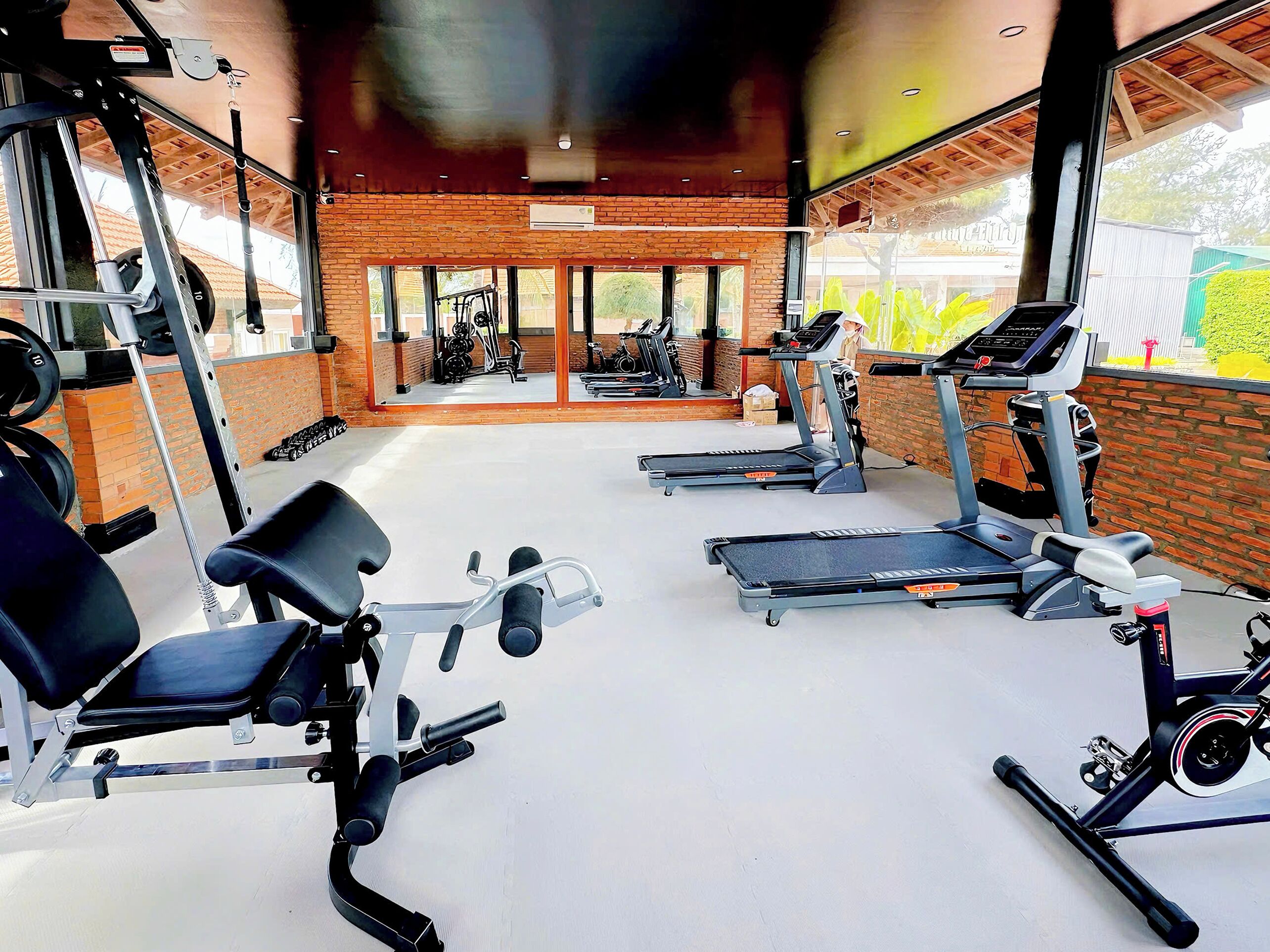 Ein Fitnessraum mit Laufbändern, Kraftgeräten und einer Bank.