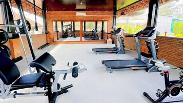 Ein Fitnessraum mit Laufbändern, Kraftgeräten und einer Bank.