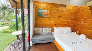 Une chambre avec un mur en bois, un lit avec une literie blanche et une petite table avec une chaise.