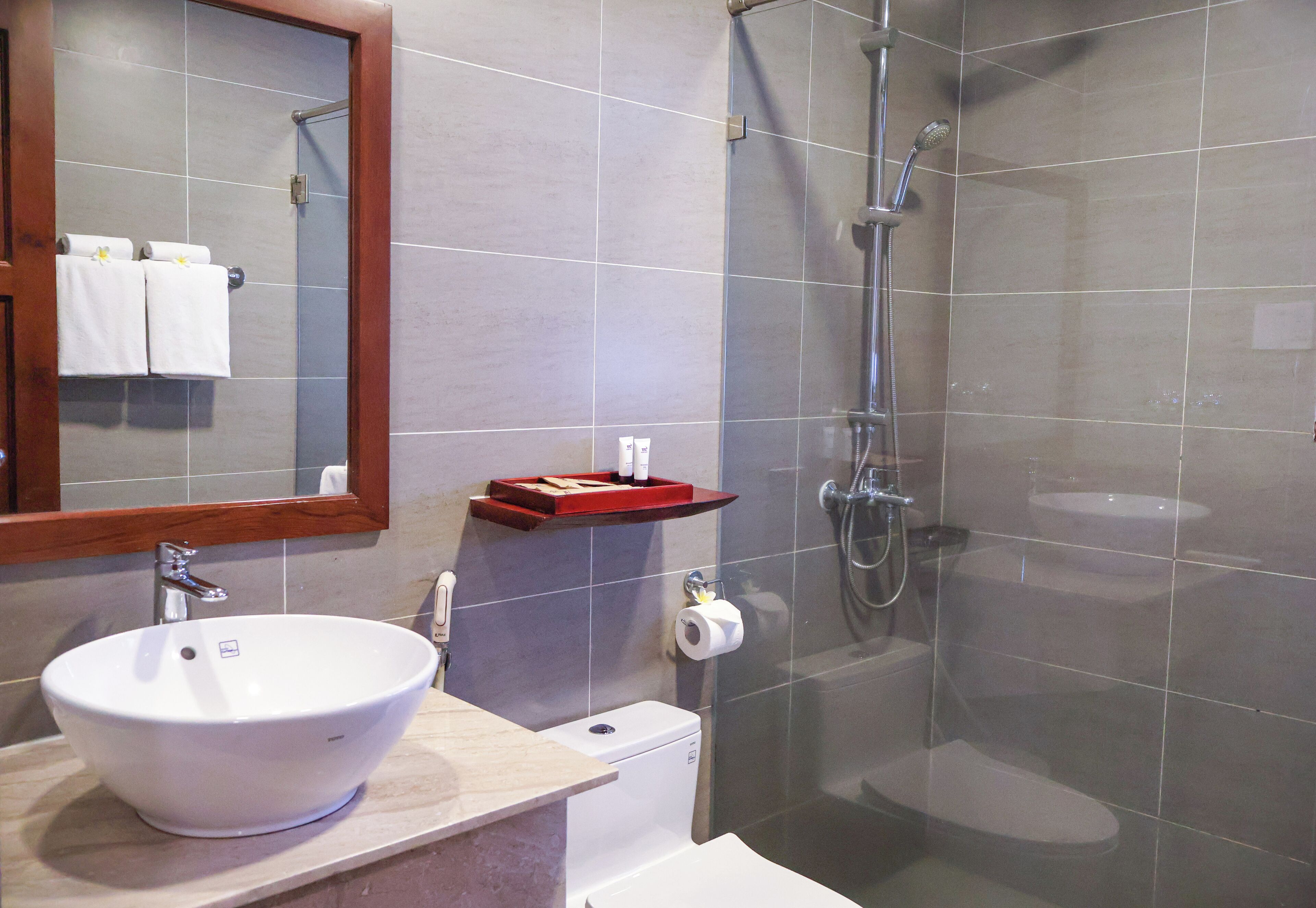 Een badkamer met een wit wastafel, een spiegel, een douche en een toilet.