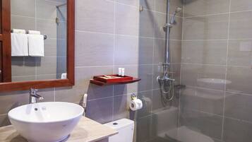 Een badkamer met een wit wastafel, een spiegel, een douche en een toilet.