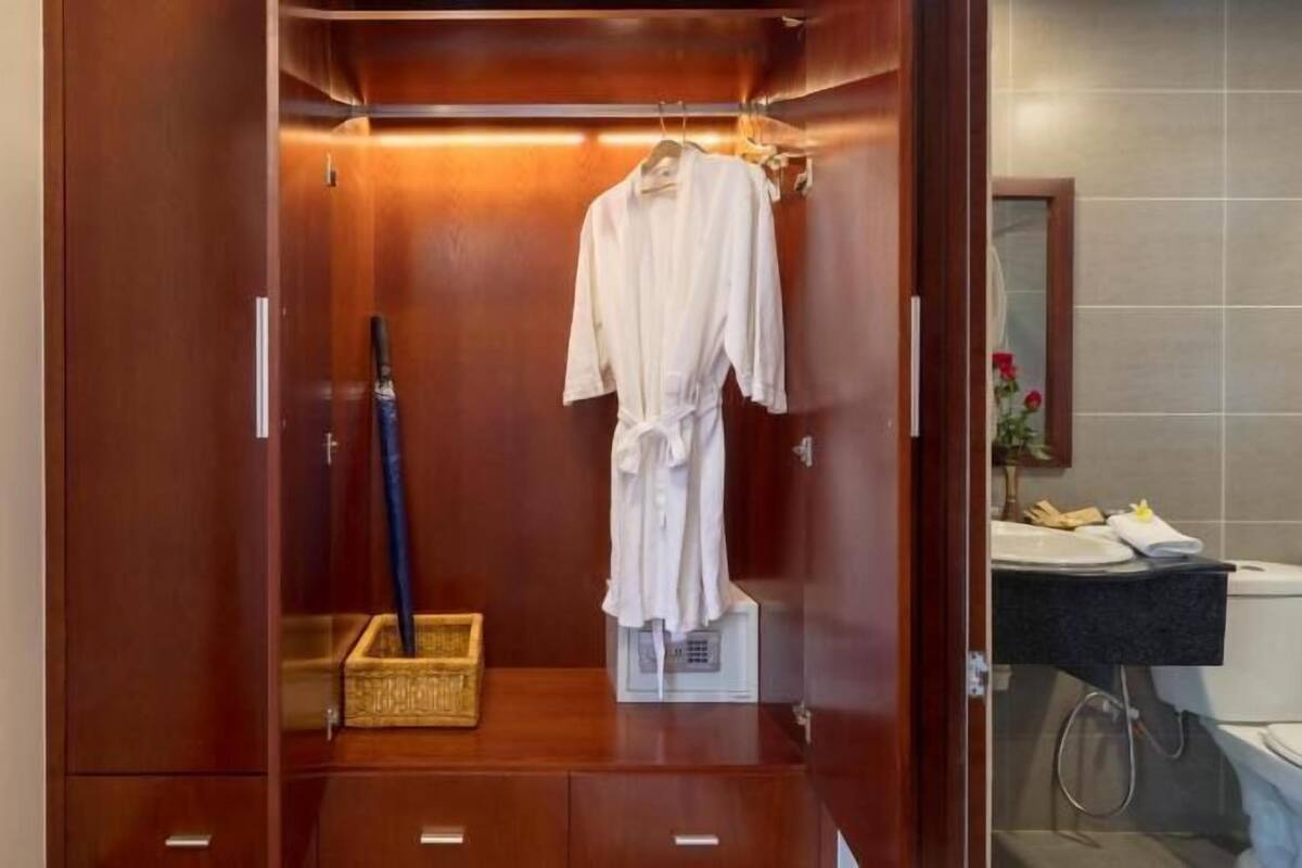 A walk-in closet with a robe hanging, a basket, and a mirror.