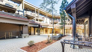 Un hotel de varios pisos con mesas al aire libre y un patio cubierto.