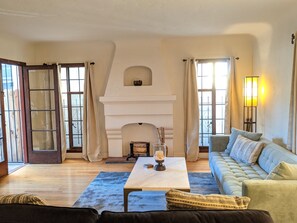 A living room with a fireplace, a sofa, a coffee table, and a lamp. - The California Mission (Long Beach)