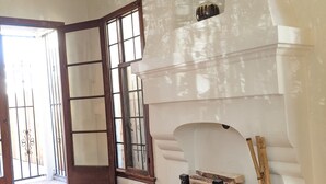 Una habitació àmplia amb una llar de foc, un sòl de fusta, una finestra gran amb vistes i una porta que dóna a l'exterior.