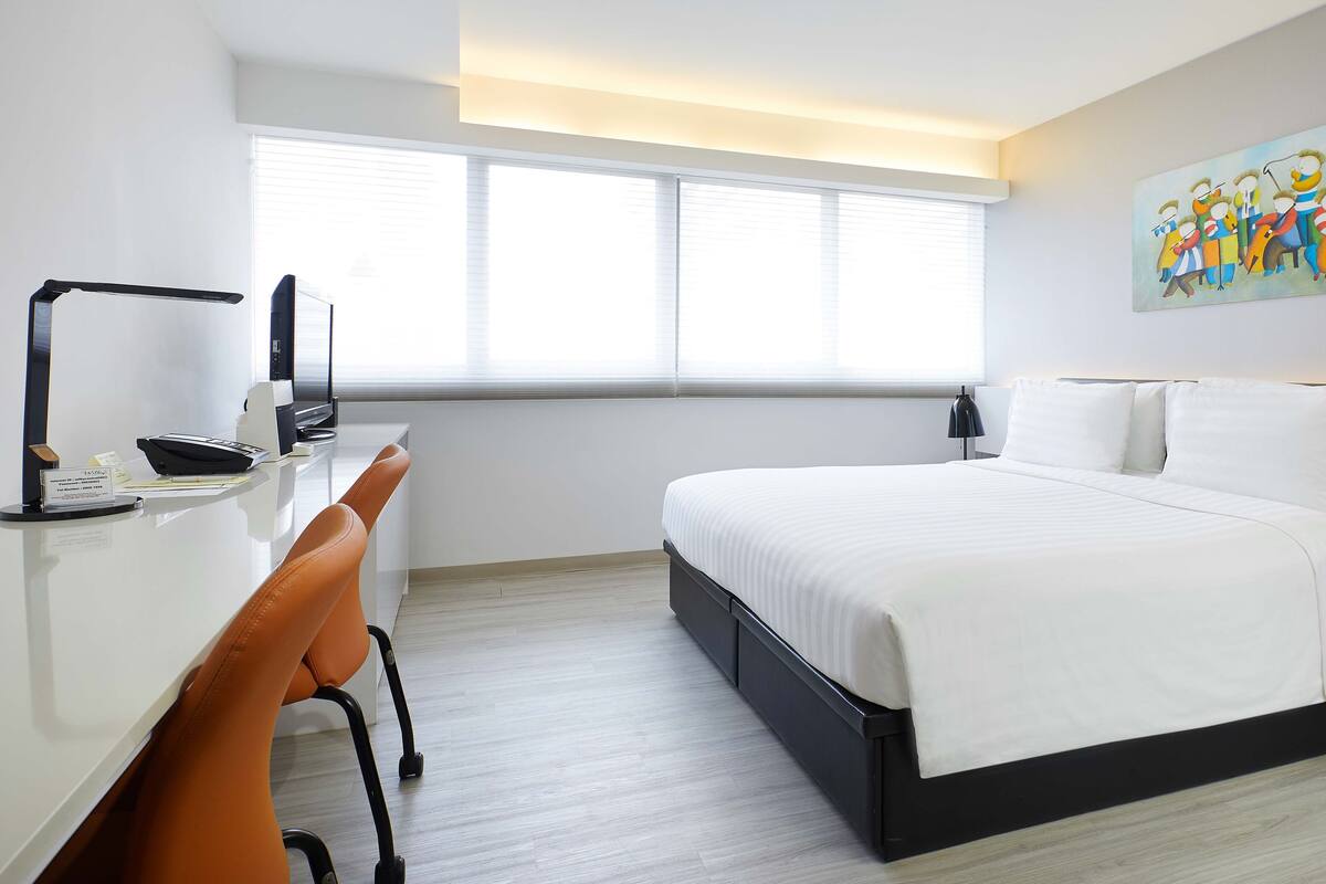Quarto de hotel moderno com uma cama grande, uma escrivaninha e uma cadeira.