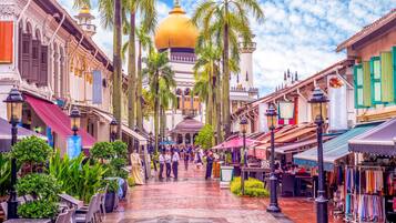 A bustling street with traditional architecture, a prominent golden dome, and a variety of shops and outdoor seating areas.
