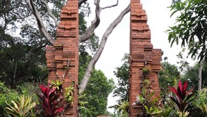 A pathway leading through a brick archway surrounded by lush greenery and a stone-tiled path. - Wilby Central Serviced Apartments (Singapore)
