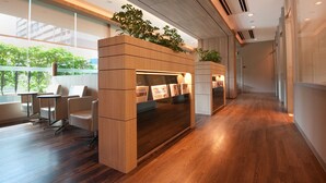 A modern office space with a wooden reception desk, seating area, and large windows offering a view of greenery outside. - Wilby Central Serviced Apartments (Singapore)