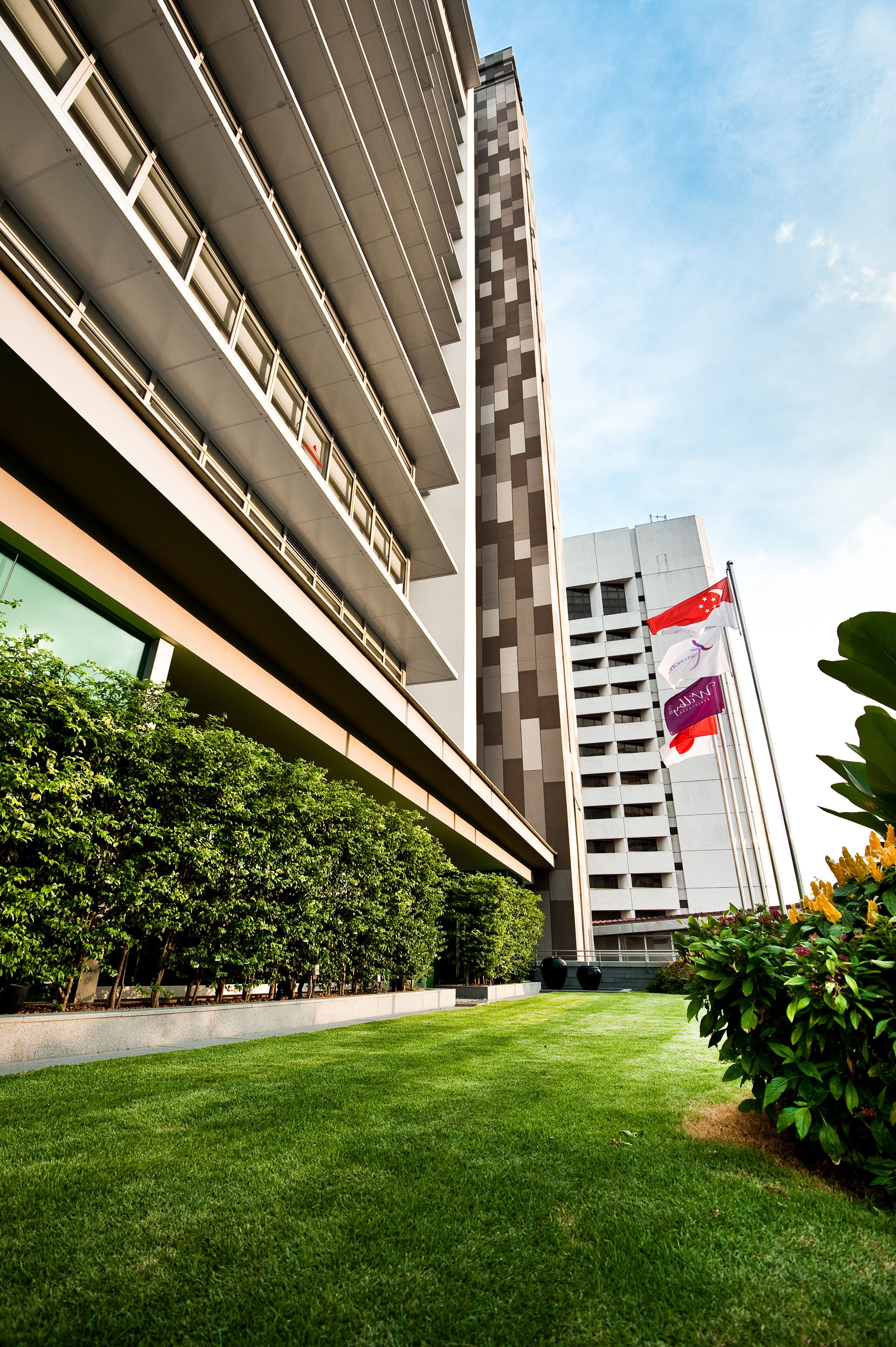 A modern building with a flat roof, a large glass facade, and a well-maintained lawn.