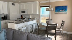 A kitchen with white cabinets, a central island, and a dining area with a table and chairs.
