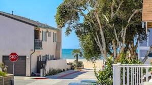 A coastal residential area with a stop sign, a white building with a garage, and a view of the beach.