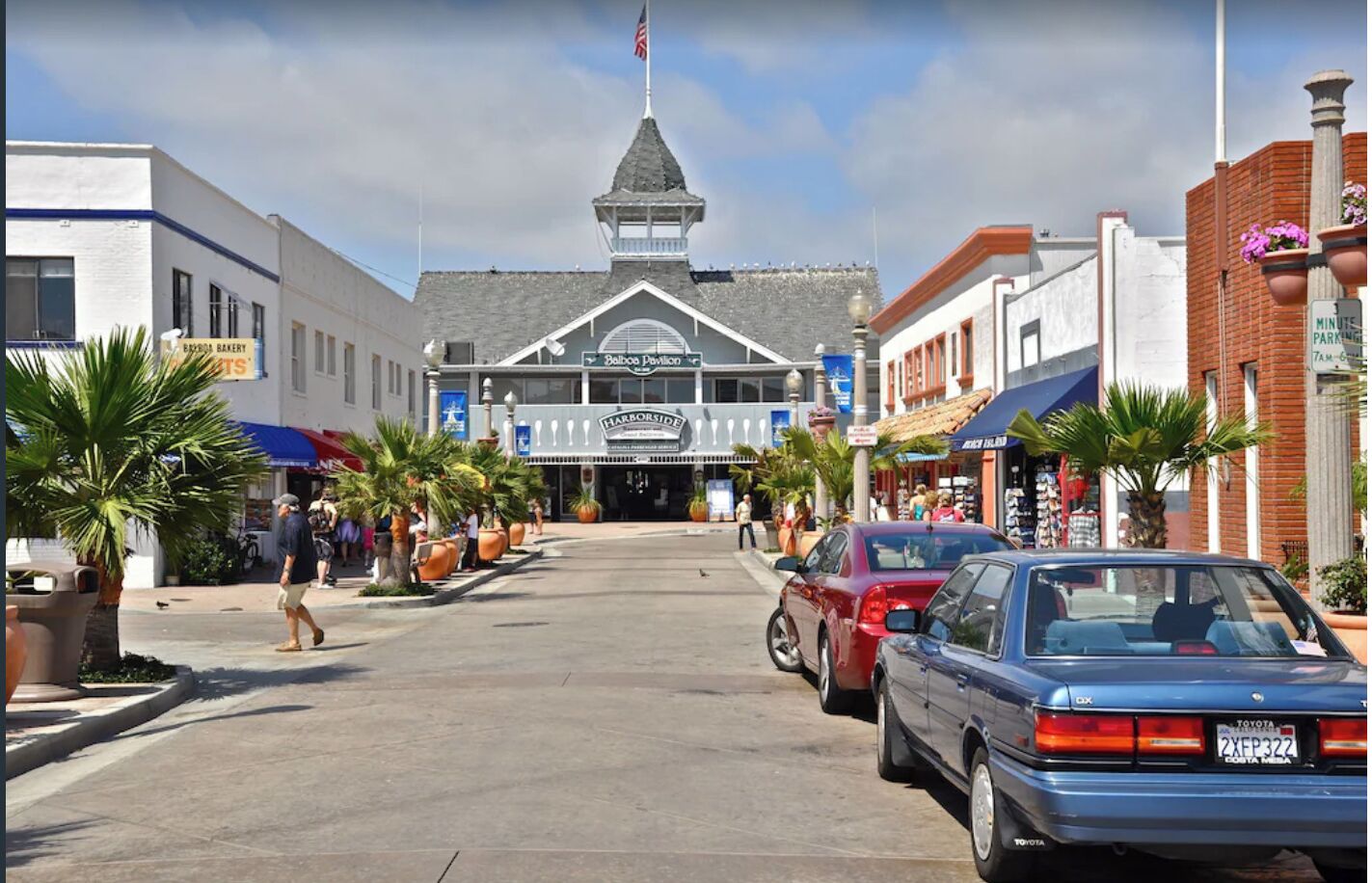 A street view with a building featuring a pointed roof and a flagpole.