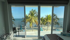 A bedroom with a large sliding glass door leading to a beach view. - BLUE DIAMOND TRANQUILITY RESORT-Private Luxury Villa - 8 King Rooms-ON THE BEACH (Stann Creek District)