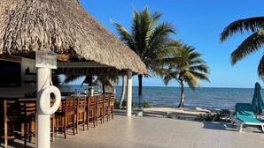 A beachside bar with wooden chairs and a thatched roof, overlooking the sea. - BLUE DIAMOND TRANQUILITY RESORT-Private Luxury Villa - 8 King Rooms-ON THE BEACH (Stann Creek District)