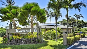 Une enseigne pour le Wavecrest Resort, avec un mur en pierre et des plantes tropicales.
