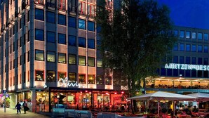 En byggnad med flera våningar, där restaurangen ”Olivia” ligger på bottenvåningen, med uteservering, och en skylt med texten ”ARNTZENDEBES” på den övre våningen.