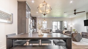 A modern kitchen with dark countertops, a large island, and a dining area with a wooden table and chairs. - Brand new Bishop Arts Condo-Right in the middle of it all! Three bathrooms! (Dallas)