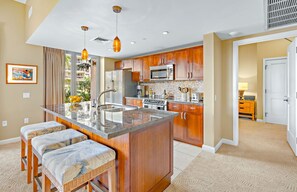 A kitchen with a central island, wooden cabinets, a microwave, and a sink.