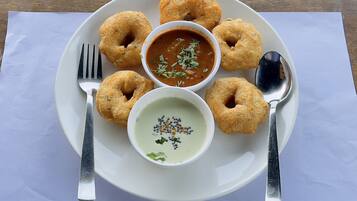 A plate with six fried dough rings and two bowls of dipping sauces on a white napkin.
