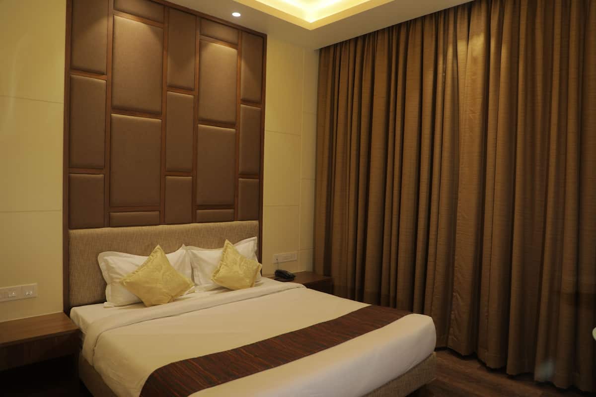A hotel room with a large bed, a headboard with a geometric design, a bedside table, and a curtain.
