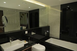Un baño moderno con un espejo grande, dos lavamanos, un inodoro y una bañera.