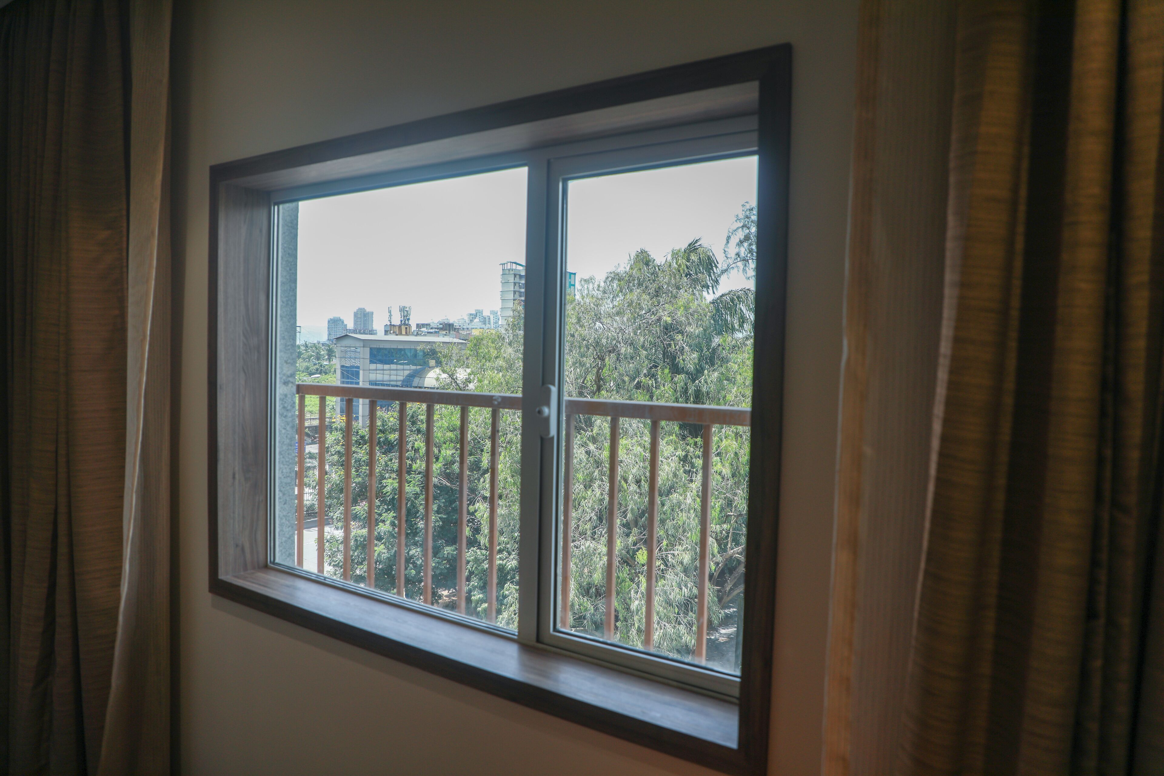 Una ventana con vistas a un paisaje urbano y zonas verdes.