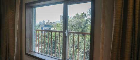Una ventana con vistas a un paisaje urbano y zonas verdes.